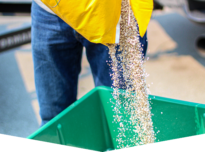 Pouring contents from bag into green container.